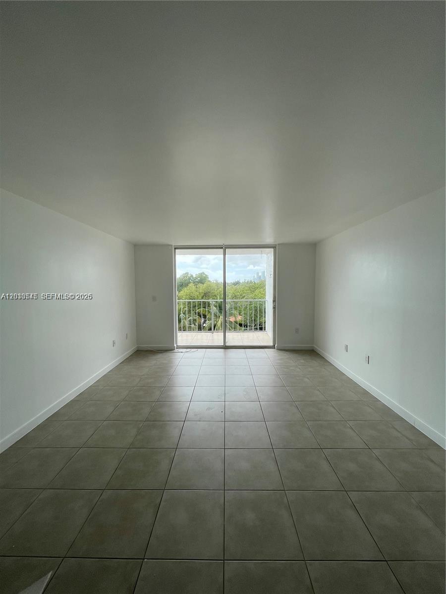 An empty room with light-colored tile flooring and a sliding glass door leading to a balcony — 700 NE 63rd St # D606, Miami FL 33138, MIAMI, FL