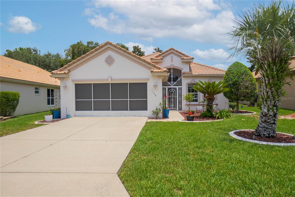 A single-story house with a screened garage door, a tiled roof, and a front lawn — 1148 W DIAMOND SHORE LOOP, HERNANDO, FL