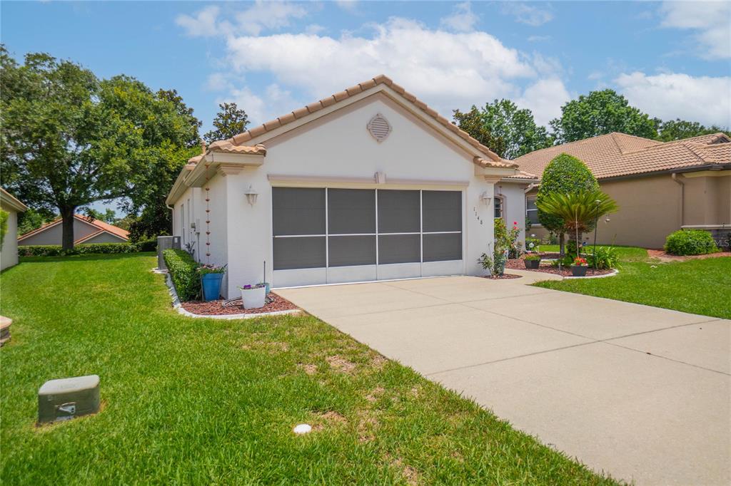 A single-story house with a beige stucco exterior, a screened garage door, and a driveway — 1148 W DIAMOND SHORE LOOP, HERNANDO, FL
