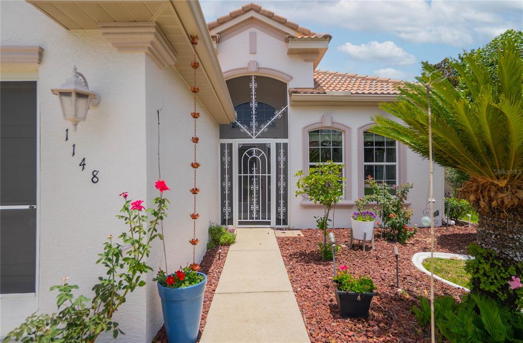 A concrete walkway leads to the front entrance of a house with a decorative screen door — 1148 W DIAMOND SHORE LOOP, HERNANDO, FL