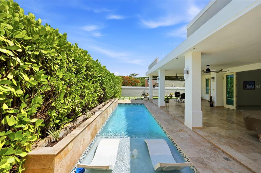 A narrow lap pool with two lounge chairs sits beside a covered patio and hedge — Bloque LN SOLAR 27, CAGUAS, PR