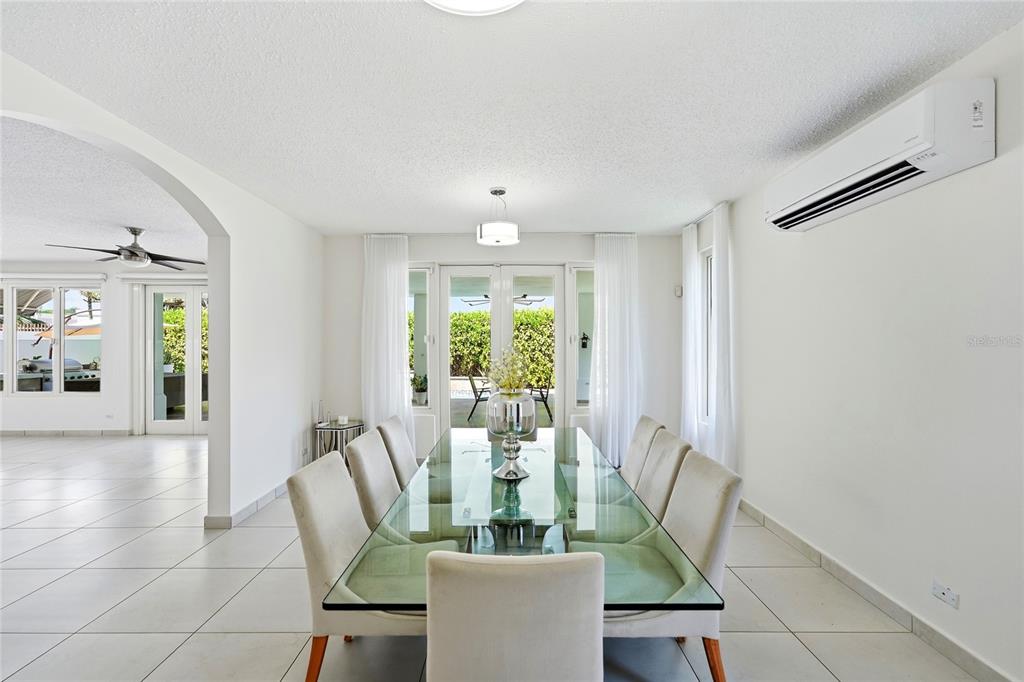 A dining room features a glass table, upholstered chairs, white walls, and a wall-mounted air conditioner — Bloque LN SOLAR 27, CAGUAS, PR