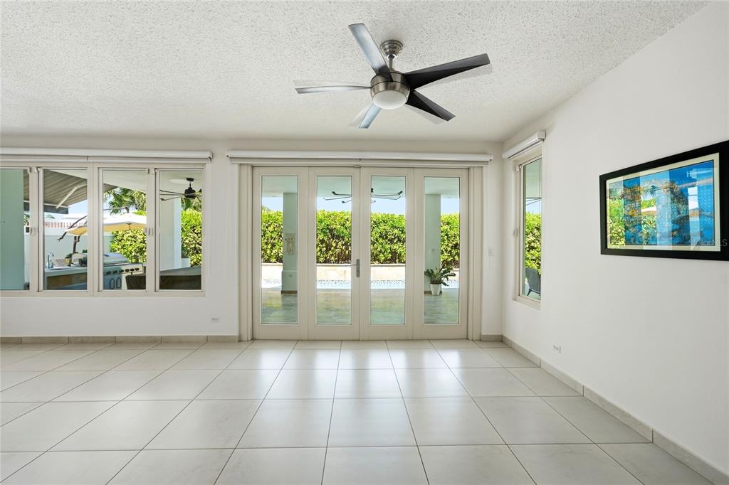 A bright, empty room with white tile floors, a ceiling fan, and glass patio doors — Bloque LN SOLAR 27, CAGUAS, PR