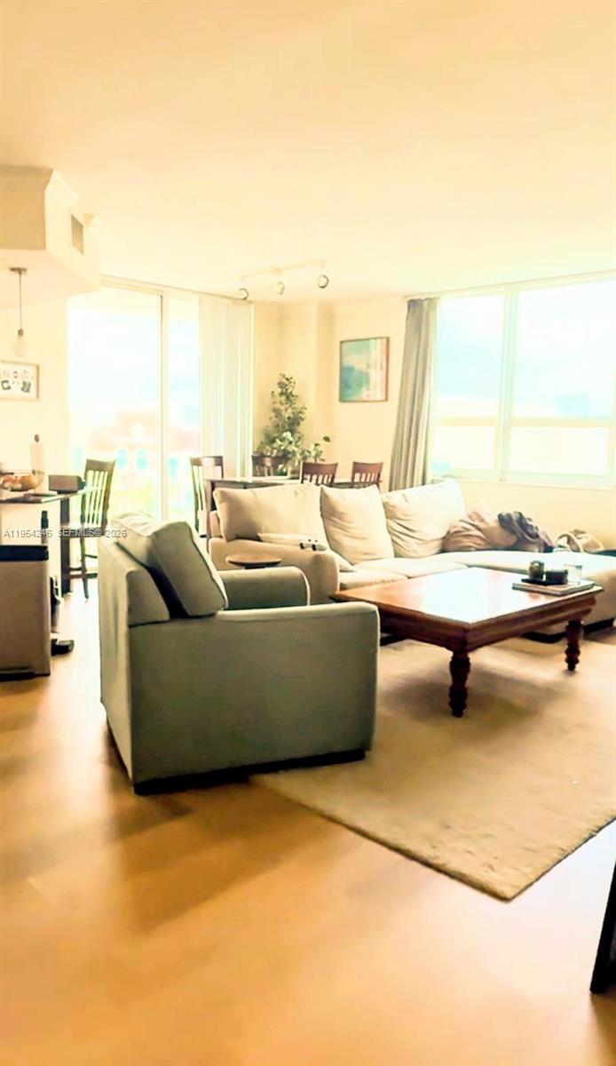 A living room features a light-colored sectional sofa, a wooden coffee table, and large windows — 2000 N Bayshore Dr # 801, Miami FL 33137, MIAMI, FL