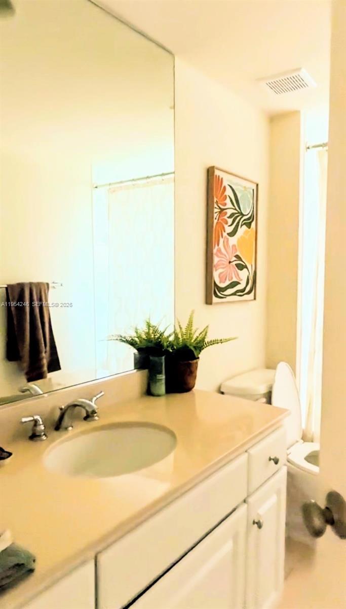 A bathroom features a white vanity with a beige countertop, a mirror, and wall art — 2000 N Bayshore Dr # 801, Miami FL 33137, MIAMI, FL
