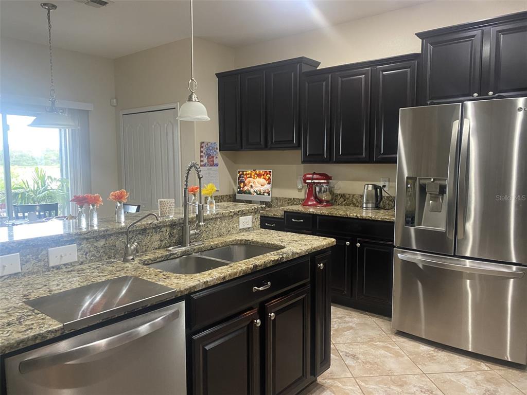 A kitchen features dark wood cabinets, granite countertops, stainless steel appliances, and a center island — 408 19TH STREET NW, RUSKIN, FL