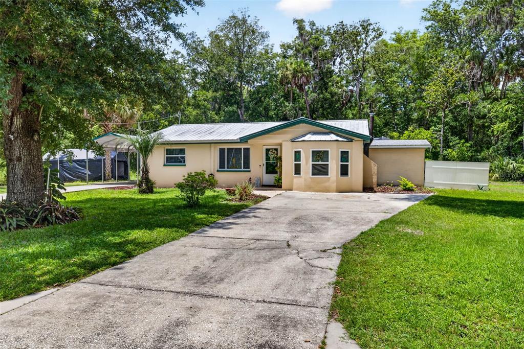 A single-story house with a metal roof, concrete driveway, and surrounding trees — 5304 S JAMES TERRACE, HOMOSASSA, FL