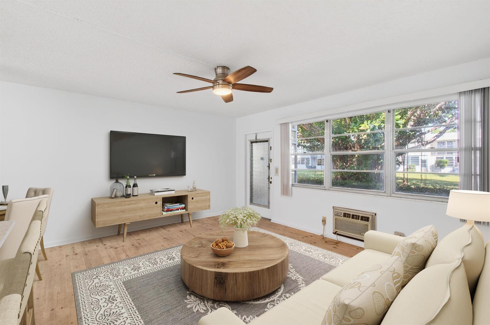 A living room features a wood-toned media console, a round coffee table, and a ceiling fan — 247 Ventnor R, Deerfield Beach FL 33442, DEERFIELD BEACH, FL