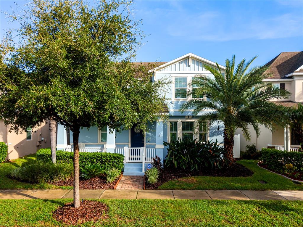 A two-story light blue house with a front porch, a palm tree, and a large tree — 14735 SNOWY EGRET STREET, WINTER GARDEN, FL