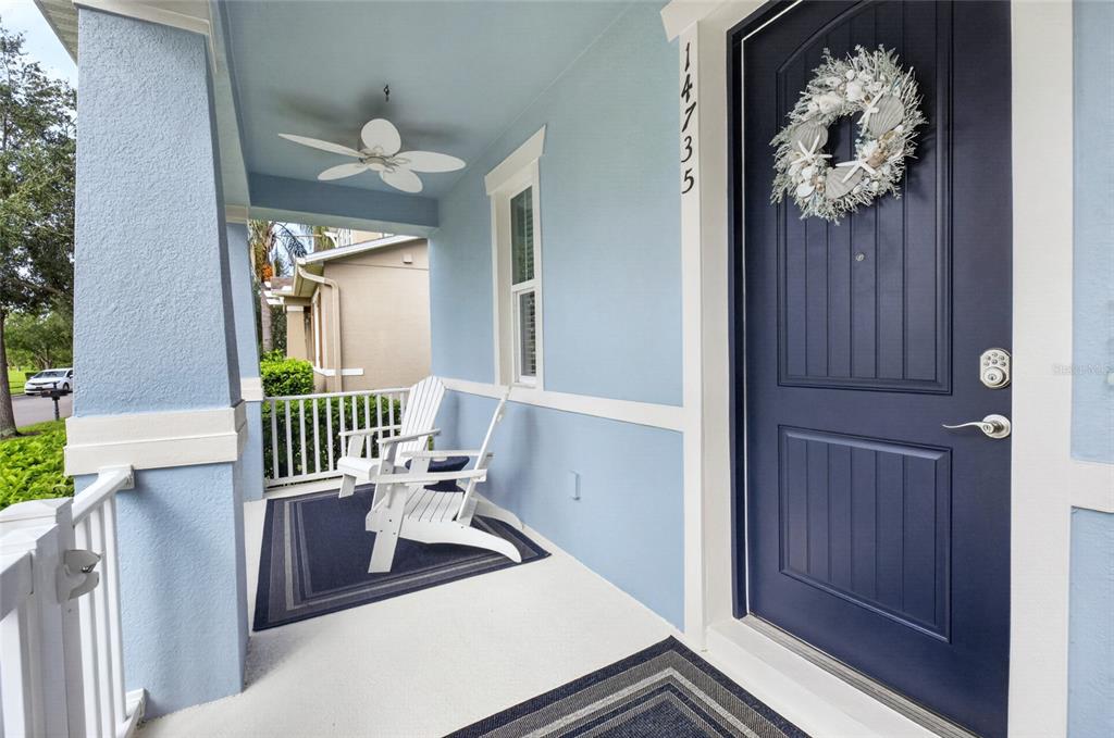 A light blue front porch features a dark blue door, white chairs, and a ceiling fan — 14735 SNOWY EGRET STREET, WINTER GARDEN, FL