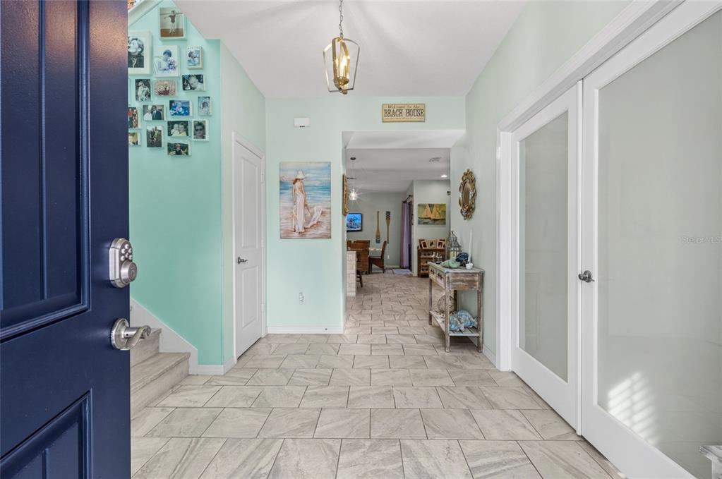 A bright entryway features light green walls, tile flooring, a gallery wall, and a pendant light — 14735 SNOWY EGRET STREET, WINTER GARDEN, FL
