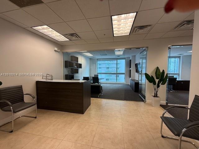 An office reception area features a dark wood desk, two chairs, and glass-walled offices — 175 SW 7th St # 1605, Miami FL 33130, MIAMI, FL