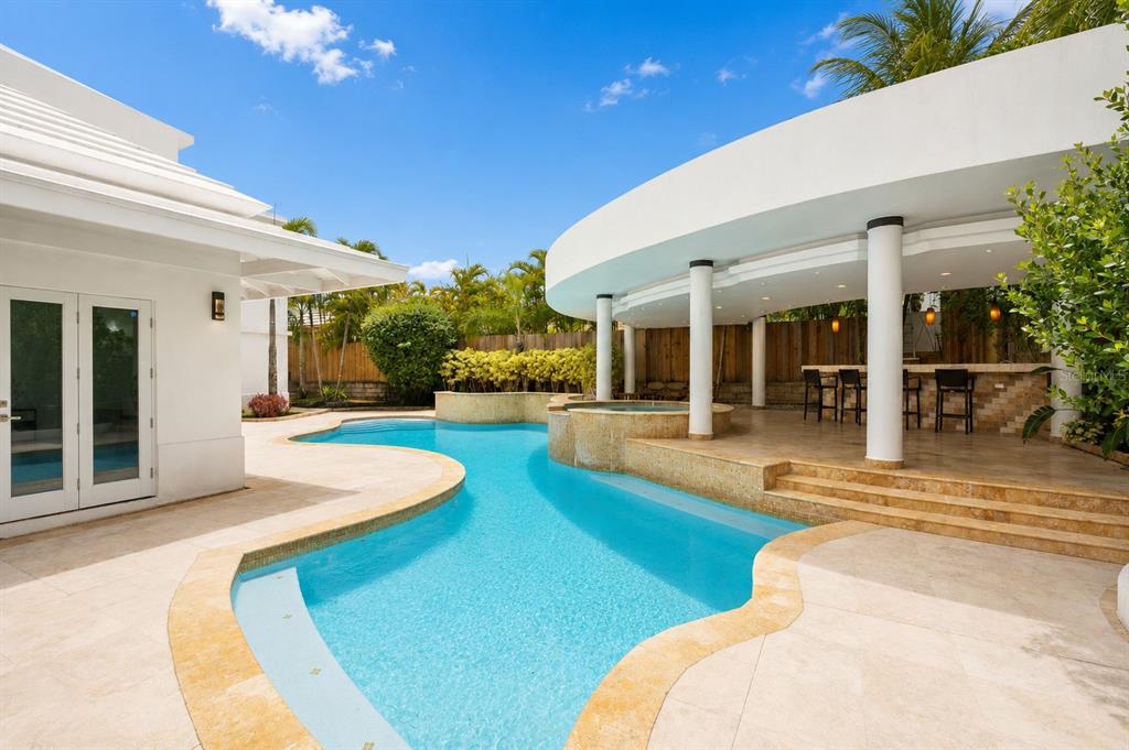 A swimming pool with a hot tub sits beside a covered patio with a bar — 16 CALLE PALMA DE COCO, DORADO, PR