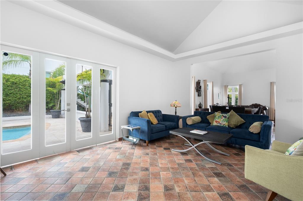A living room with tiled floors, blue sofas, and glass doors opening to a pool — 16 CALLE PALMA DE COCO, DORADO, PR