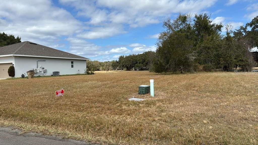 A vacant, grassy residential lot sits next to a house under a cloudy sky — 2231 MARSHFIELD PRESERVE WAY, KISSIMMEE, FL