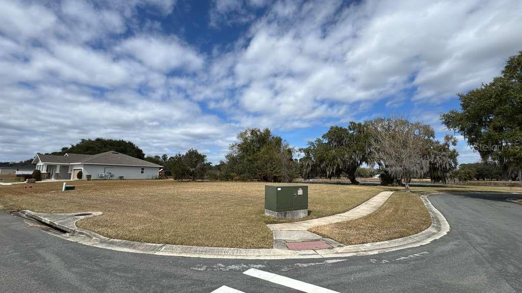 A corner lot with a green utility box sits next to a house under clouds — 2231 MARSHFIELD PRESERVE WAY, KISSIMMEE, FL