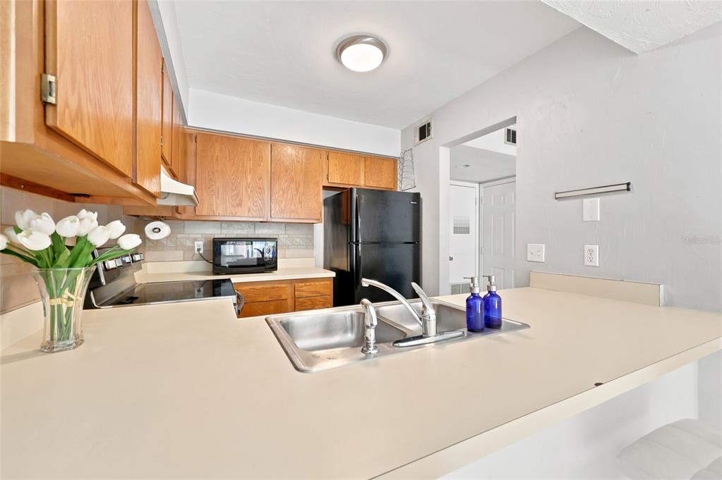 A kitchen features wood cabinets, a black refrigerator, a double sink, and beige countertops — 4431 SW 21ST LANE, GAINESVILLE, FL