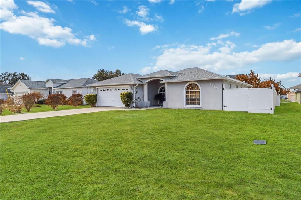 A single-story house with a gray exterior, a two-car garage, and a white vinyl fence — 1912 MANATEE DR, POINCIANA, FL