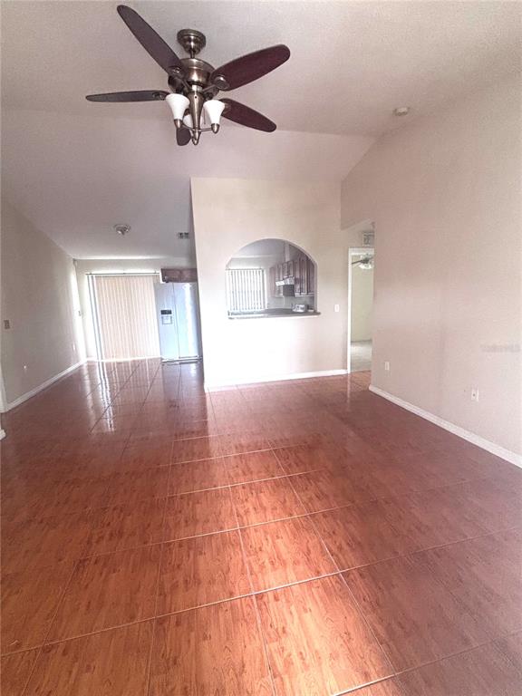 An open living area features wood-look tile flooring, a ceiling fan, and an arched kitchen pass-through — 1912 MANATEE DR, POINCIANA, FL