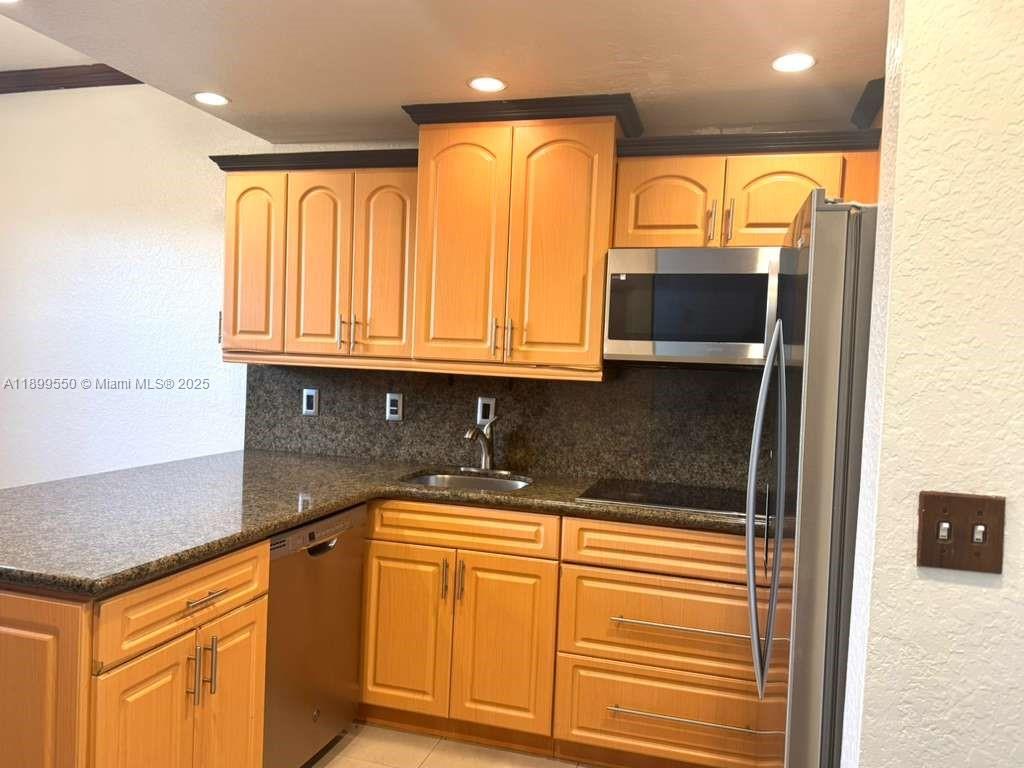 A kitchen features light wood cabinets, dark granite countertops, and stainless steel appliances — 420 E 1st Ave # B204, Hialeah FL 33010, HIALEAH, FL