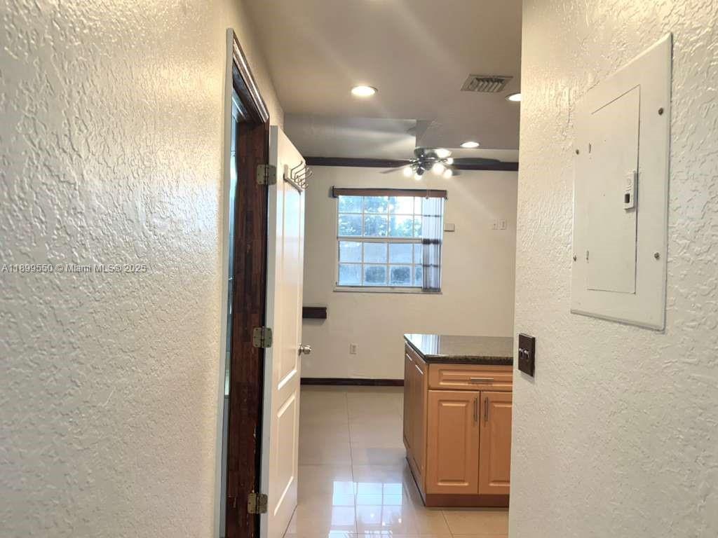 A view through a doorway into a kitchen featuring light wood cabinets and tile flooring — 420 E 1st Ave # B204, Hialeah FL 33010, HIALEAH, FL