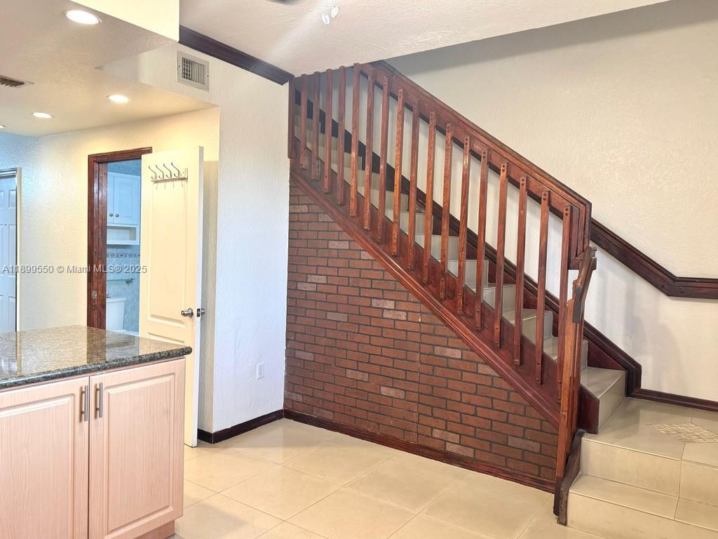 A staircase with a wooden railing stands next to a brick wall in a room — 420 E 1st Ave # B204, Hialeah FL 33010, HIALEAH, FL