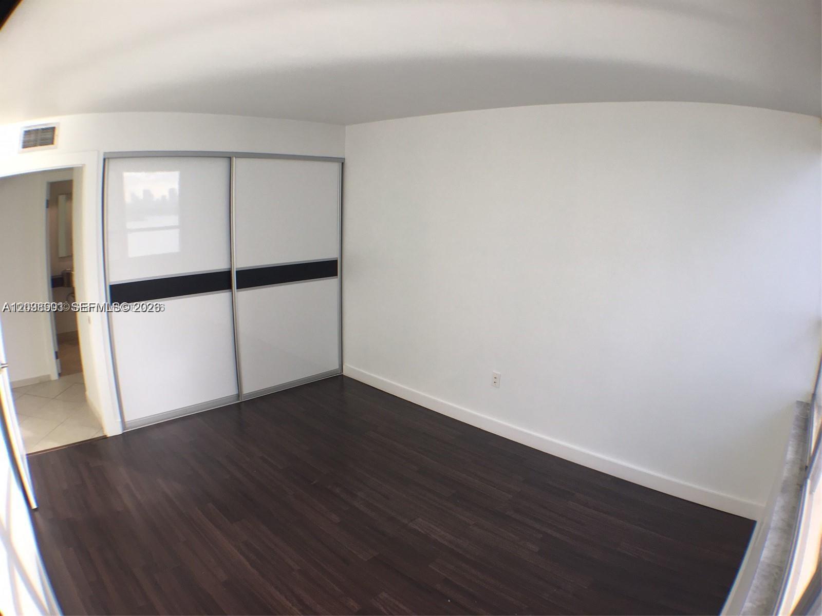 A bedroom features dark wood flooring, white walls, and a sliding-door closet — 11 Island Ave # 1505, Miami Beach FL 33139, MIAMI BEACH, FL