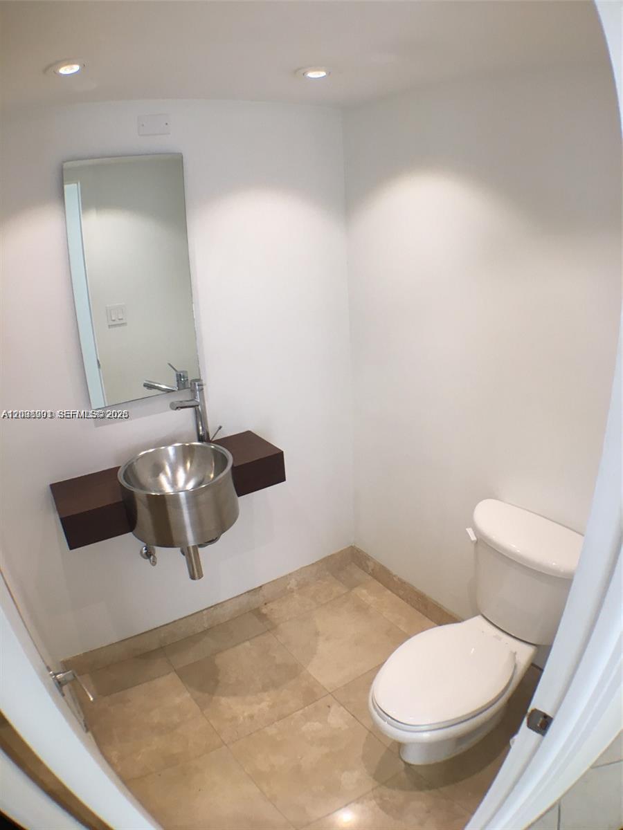 A small bathroom features a wall-mounted metal sink, a mirror, and a white toilet — 11 Island Ave # 1505, Miami Beach FL 33139, MIAMI BEACH, FL