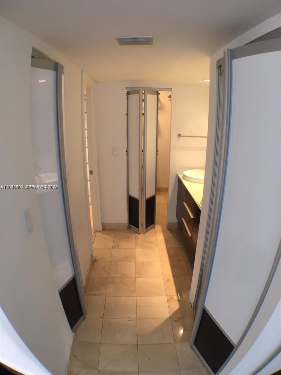 A hallway leads to a bathroom featuring a vanity, sink, and a folding door — 11 Island Ave # 1505, Miami Beach FL 33139, MIAMI BEACH, FL