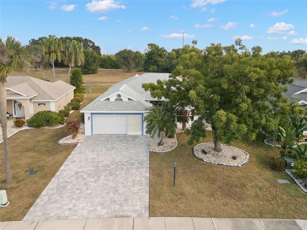 An aerial view shows a single-story house with a paved driveway and a large tree — 1911 E DEL WEBB BOULEVARD, SUN CITY CENTER, FL