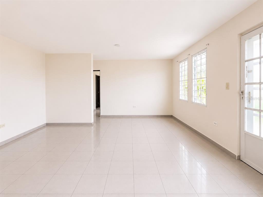 An empty room with light-colored tile flooring, beige walls, two windows, and a glass door — 461 Comm. Mariani BO. EMAJAGUA, MAUNABO, PR