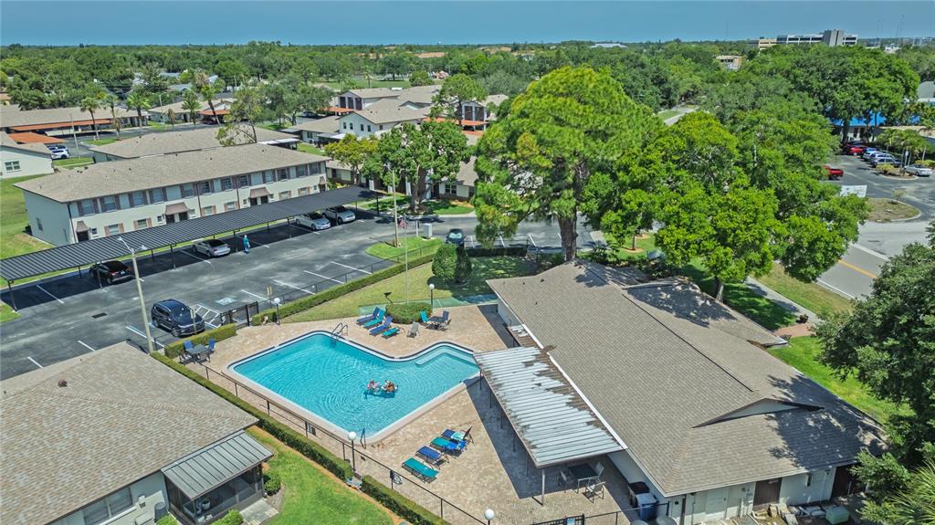An aerial view shows an apartment complex with a swimming pool, covered parking, and landscaping — 2444 ENTERPRISE ROAD UNIT 29, CLEARWATER, FL