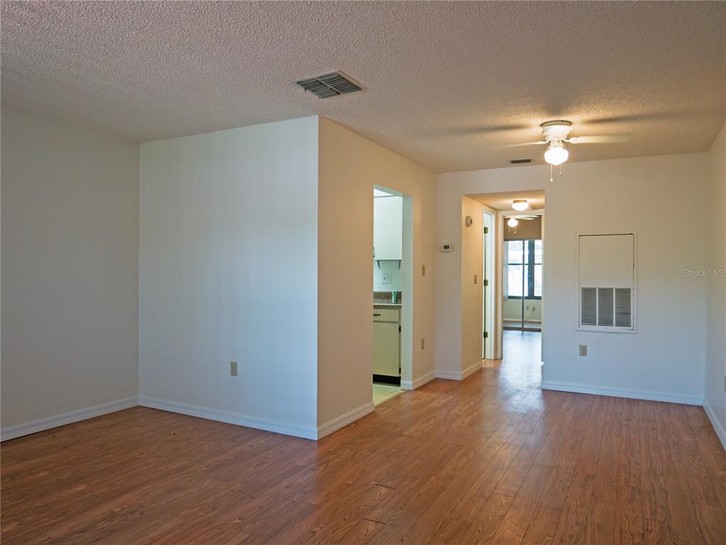 An interior view of a room with wood-look flooring, a ceiling fan, and an open doorway — 2444 ENTERPRISE ROAD UNIT 29, CLEARWATER, FL