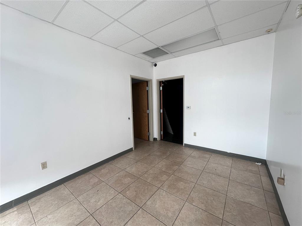 An empty office room features white walls, a tiled floor, and two open doorways — 1700 35TH STREET UNIT 103, ORLANDO, FL