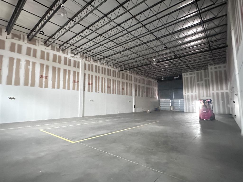 An empty warehouse interior features high ceilings, exposed metal trusses, and unfinished drywall walls — 1700 35TH STREET UNIT 103, ORLANDO, FL