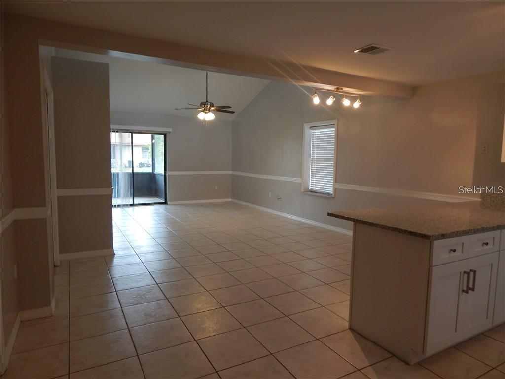 A tiled living area features a vaulted ceiling, ceiling fan, and sliding glass patio doors — 307 SHERBORNE LANE, KISSIMMEE, FL