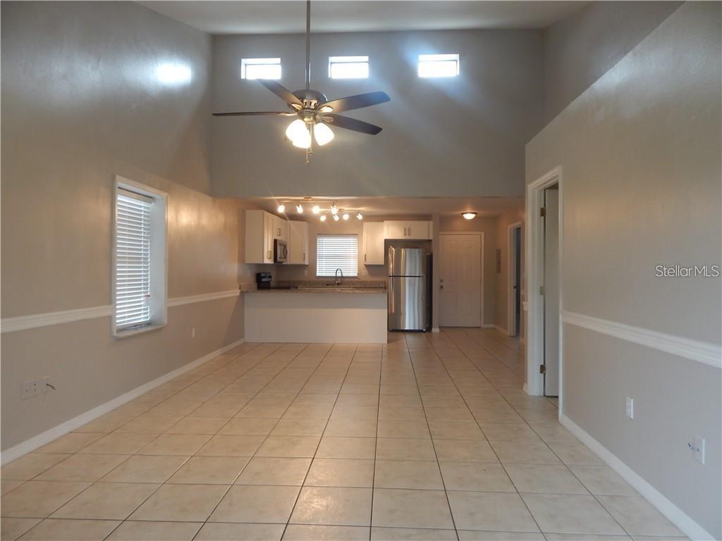 An open-concept kitchen and living area features vaulted ceilings, tile flooring, and stainless steel appliances — 307 SHERBORNE LANE, KISSIMMEE, FL