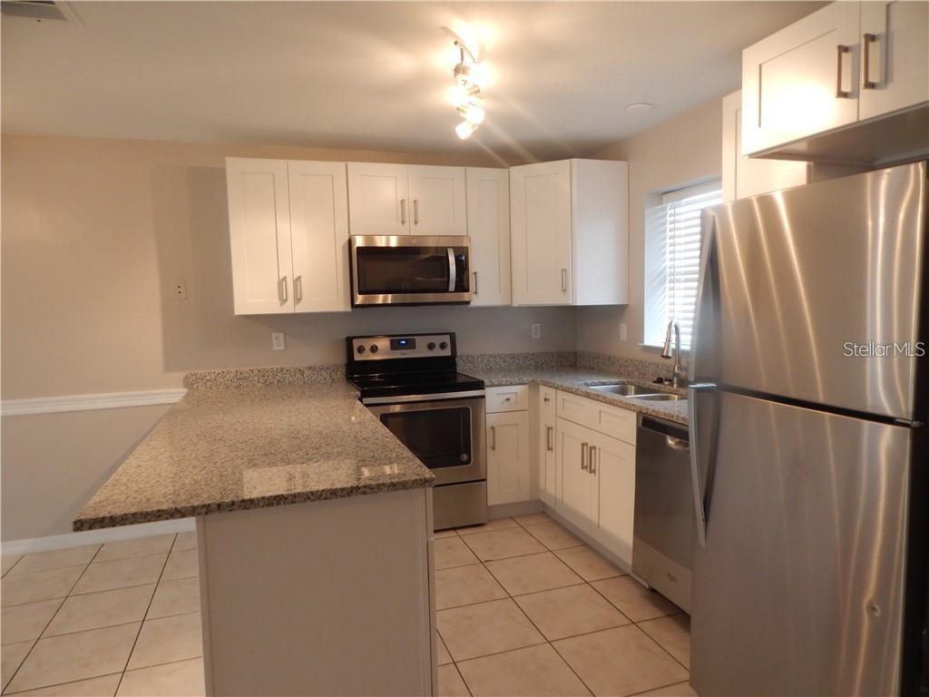 A kitchen features white cabinets, granite countertops, and stainless steel appliances — 307 SHERBORNE LANE, KISSIMMEE, FL