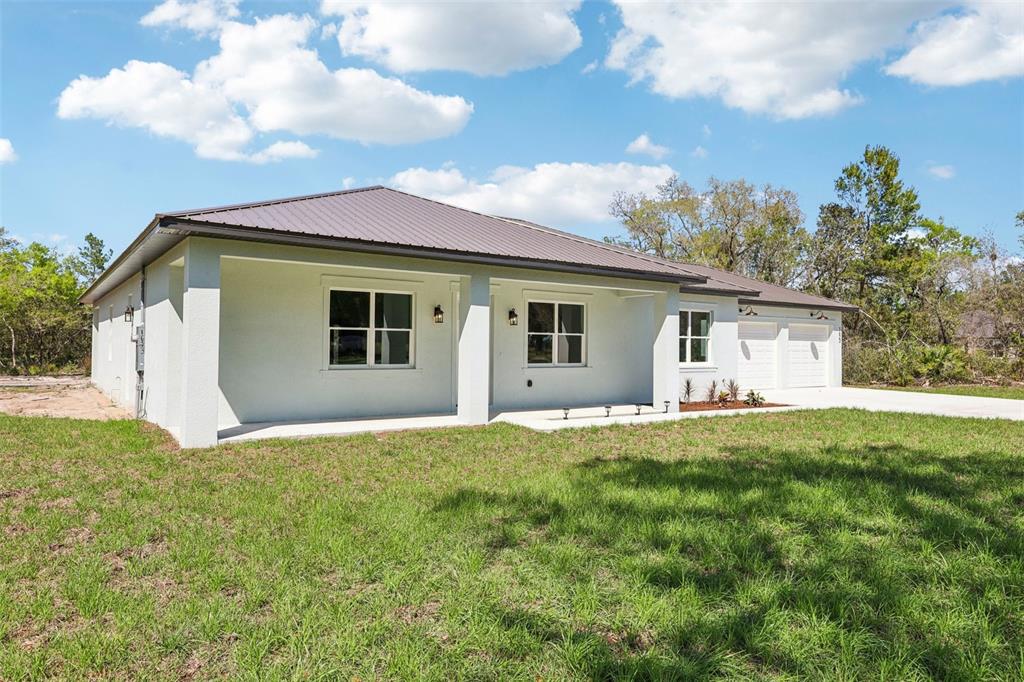 A white single-story house with a metal roof and a covered front porch — 1623 MAGNOLIA AVENUE, DELAND, FL