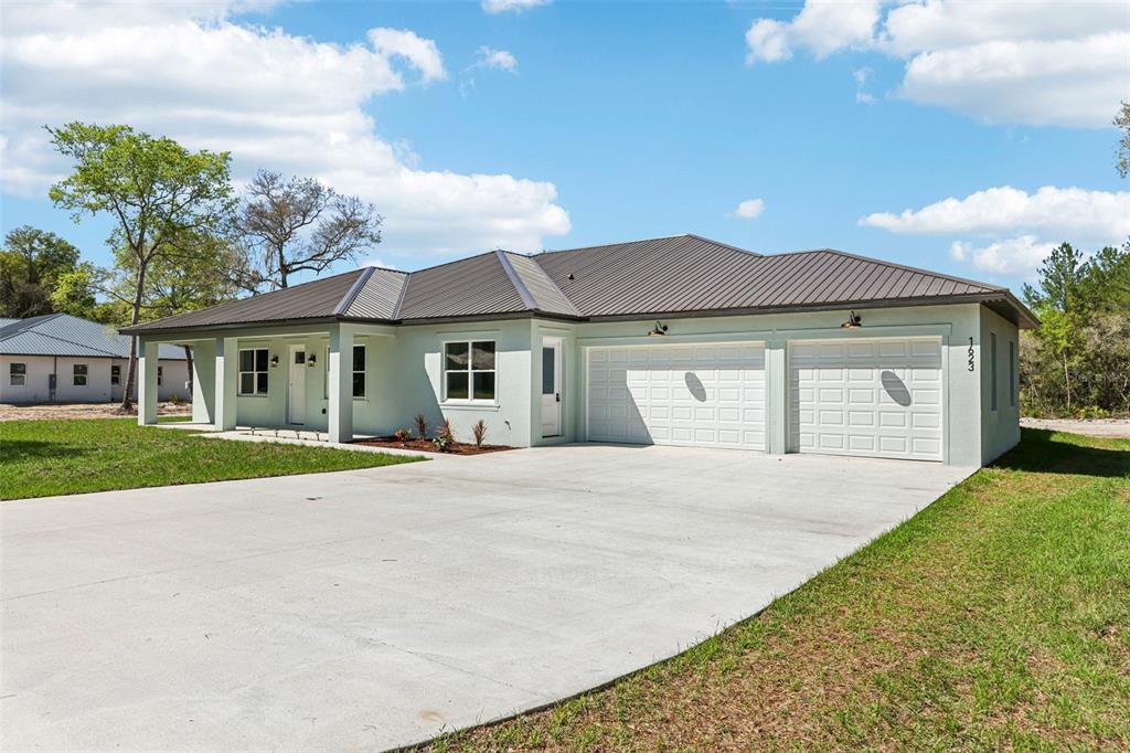 A light green single-story house with a metal roof and a two-car garage — 1623 MAGNOLIA AVENUE, DELAND, FL