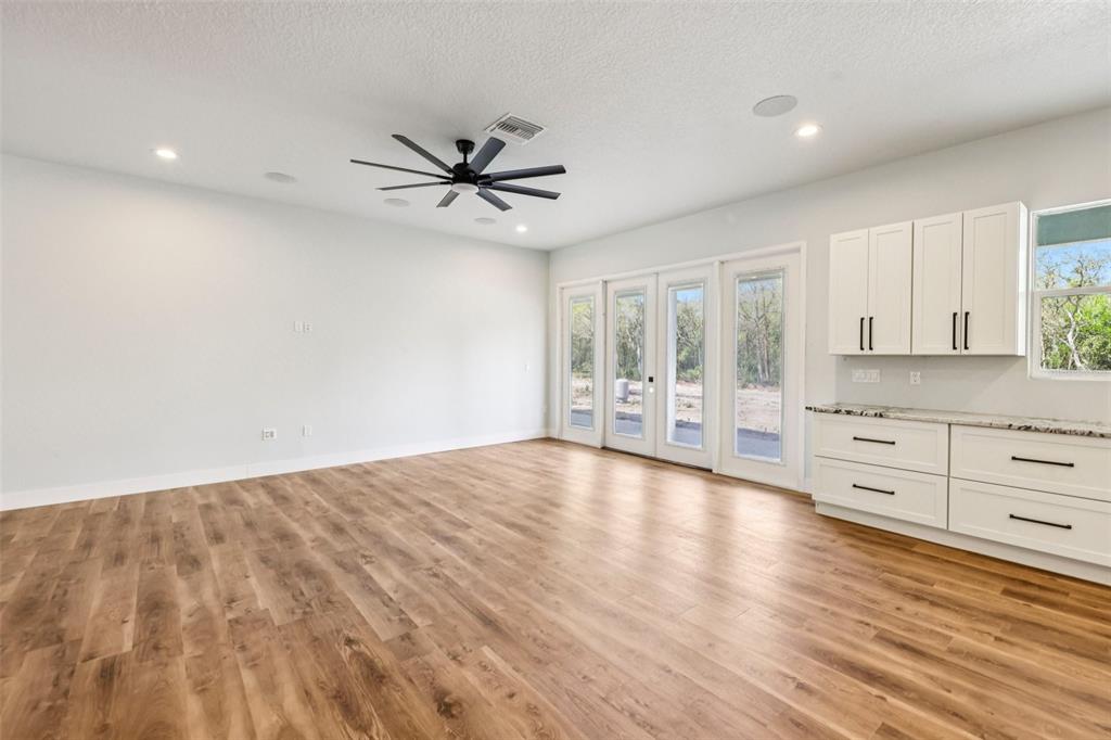 A bright living room features wood-look flooring, a ceiling fan, and white cabinetry — 1623 MAGNOLIA AVENUE, DELAND, FL
