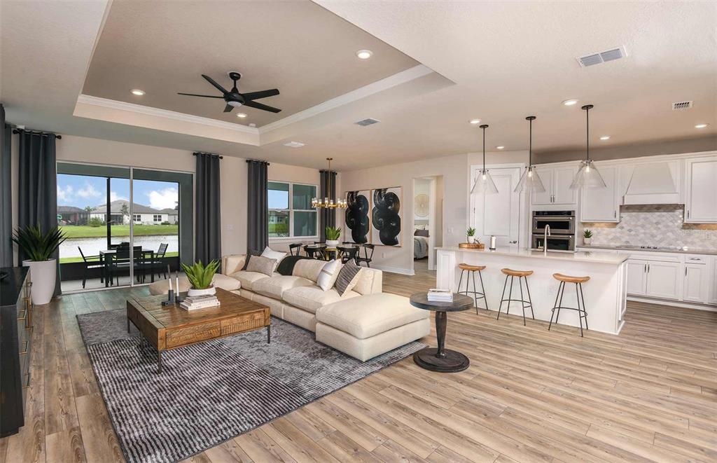 An open-concept living room and kitchen feature wood-look flooring, a tray ceiling, and sliding doors — 8582 SW 64TH STREET ROAD, OCALA, FL