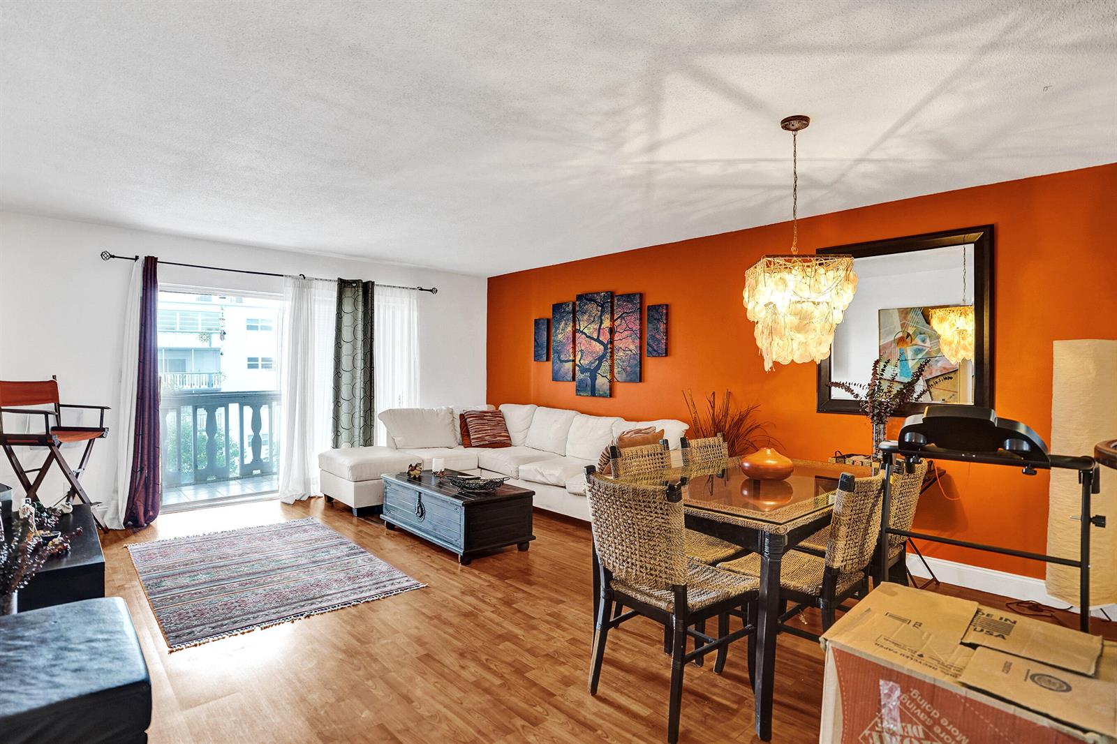 A living and dining room features an orange accent wall, white sectional, and glass table — 218 NE 12th Avenue # 401, Hallandale Beach FL 33009, HALLANDALE BEACH, FL