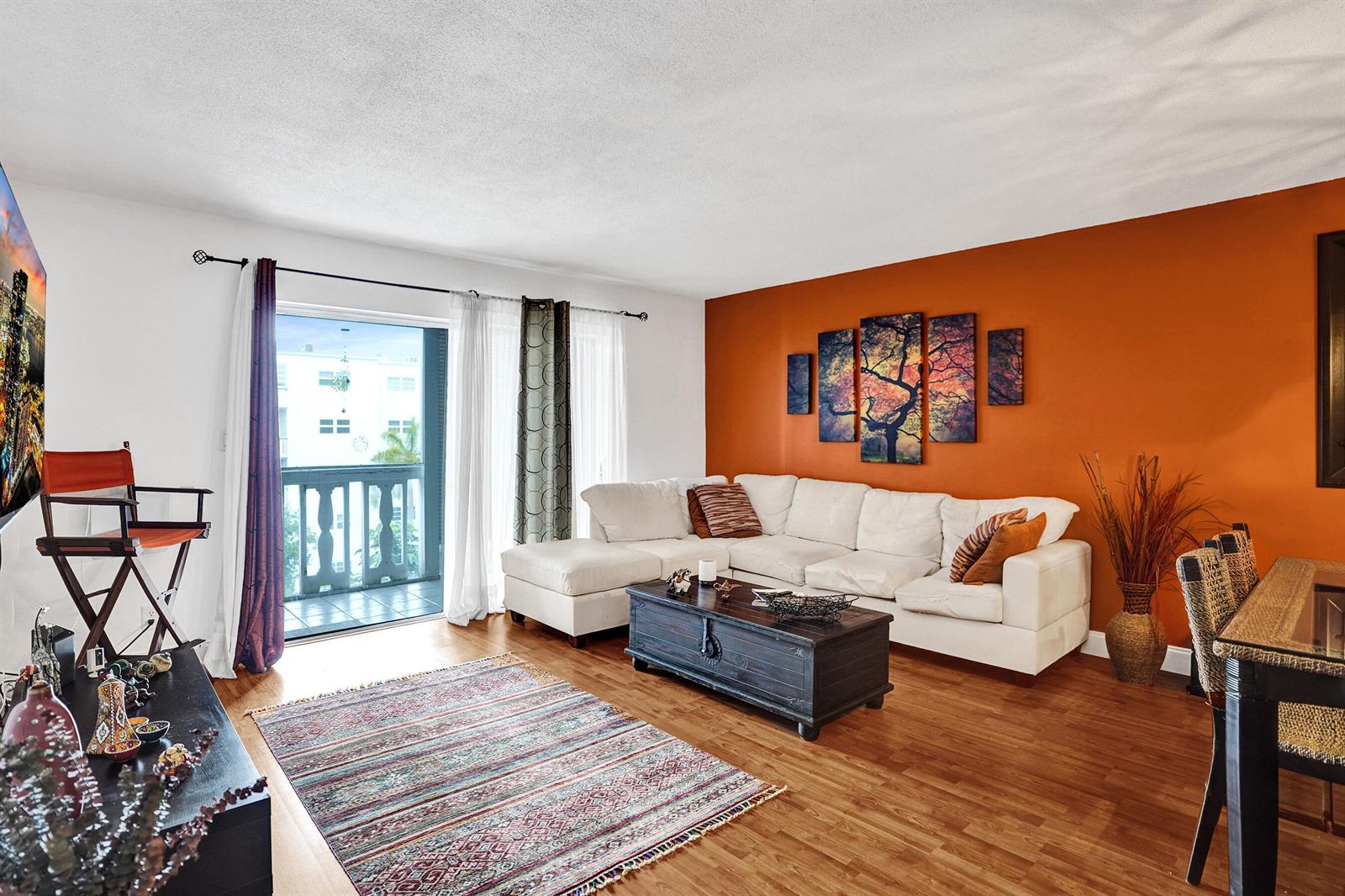 A living room features a white sectional sofa, a dark coffee table, and an orange wall — 218 NE 12th Avenue # 401, Hallandale Beach FL 33009, HALLANDALE BEACH, FL