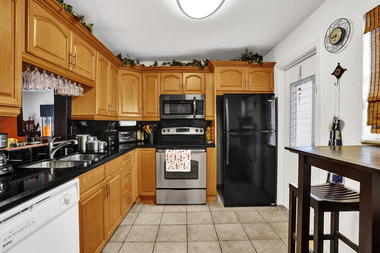 A kitchen features wooden cabinets, black countertops, stainless steel appliances, and a black refrigerator — 218 NE 12th Avenue # 401, Hallandale Beach FL 33009, HALLANDALE BEACH, FL