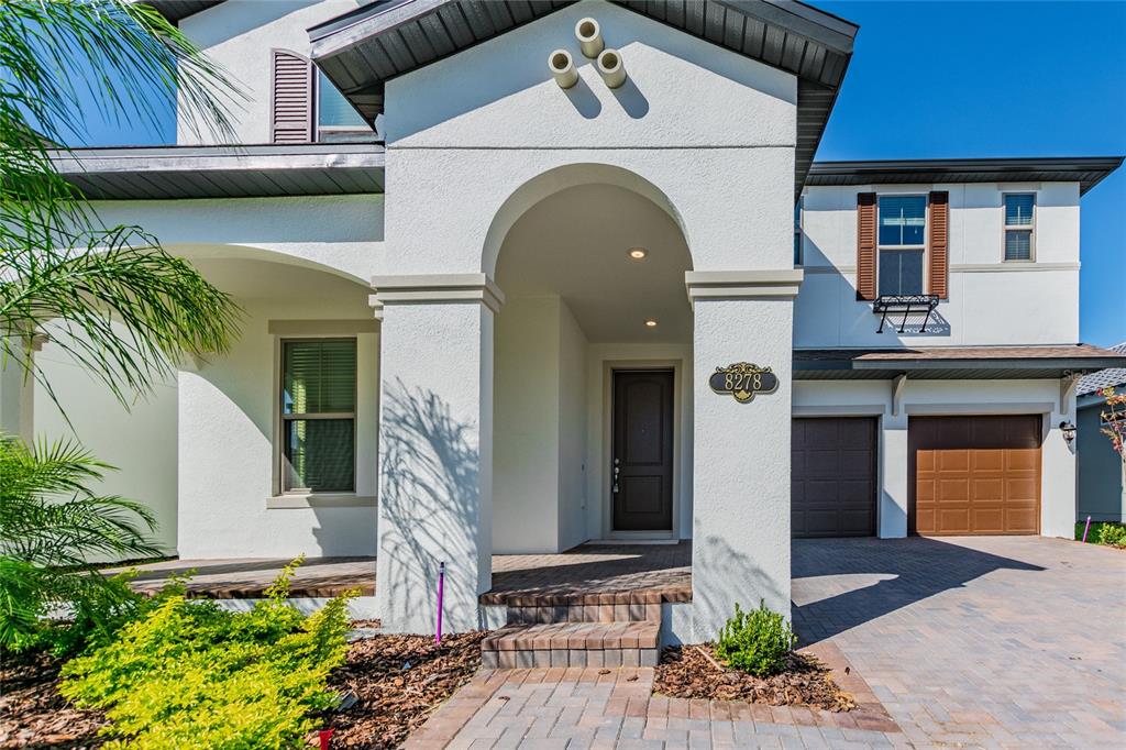 The exterior of a two-story white house features a covered entryway and two garage doors — 8278 PROCIDA ISLE LANE, WINDERMERE, FL