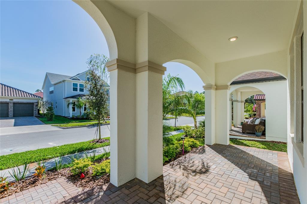 A covered brick porch features arched openings and views of a suburban street — 8278 PROCIDA ISLE LANE, WINDERMERE, FL