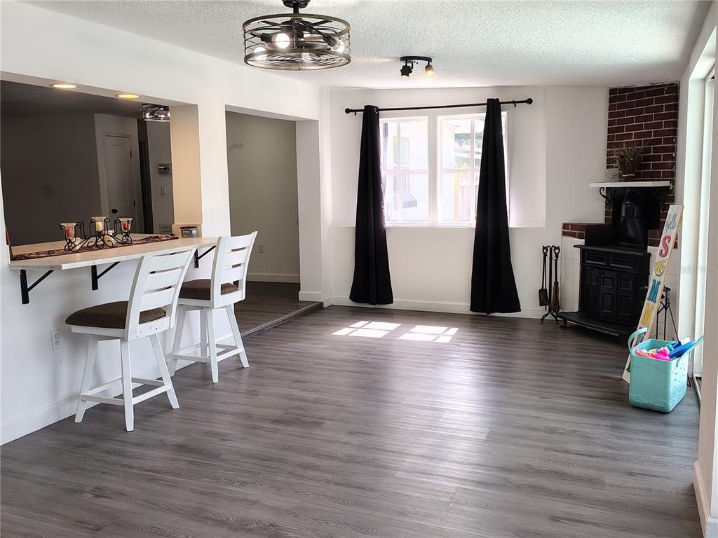 A dining area features gray wood-look flooring, a breakfast bar, and a black wood-burning stove — 415 E BERESFORD AVENUE, DELAND, FL