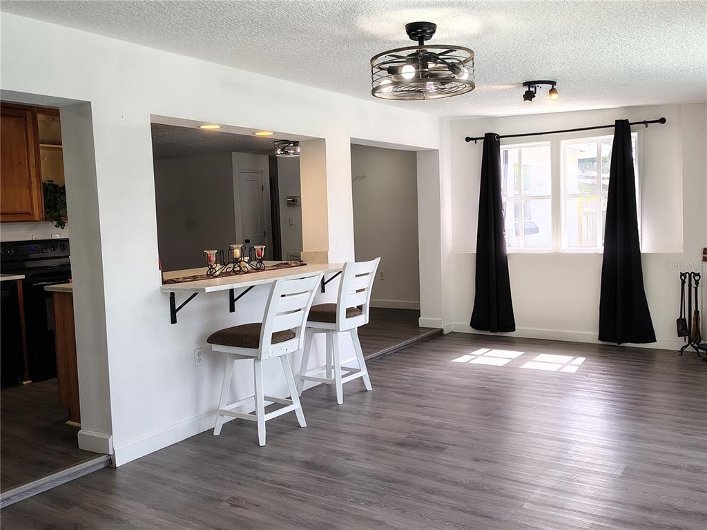 A dining area features a breakfast bar with two white stools and gray flooring — 415 E BERESFORD AVENUE, DELAND, FL
