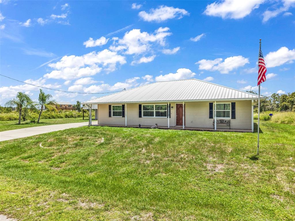 A single-story house with a metal roof and an American flag in the front yard — 30 SUCCESS DRIVE, PUNTA GORDA, FL
